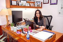 Salimah Walani seated at her office desk with computer and books.