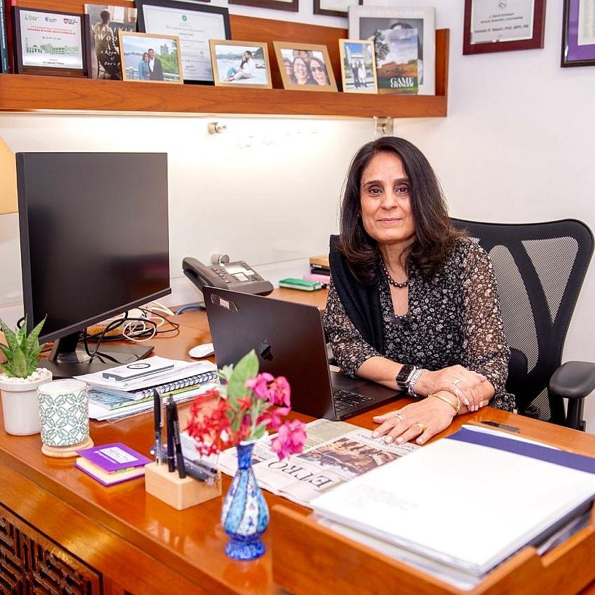 Salimah Walani seated at her office desk with computer and books.