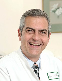 Portrait of Michael Abou-Dakn smiling in a white coat.