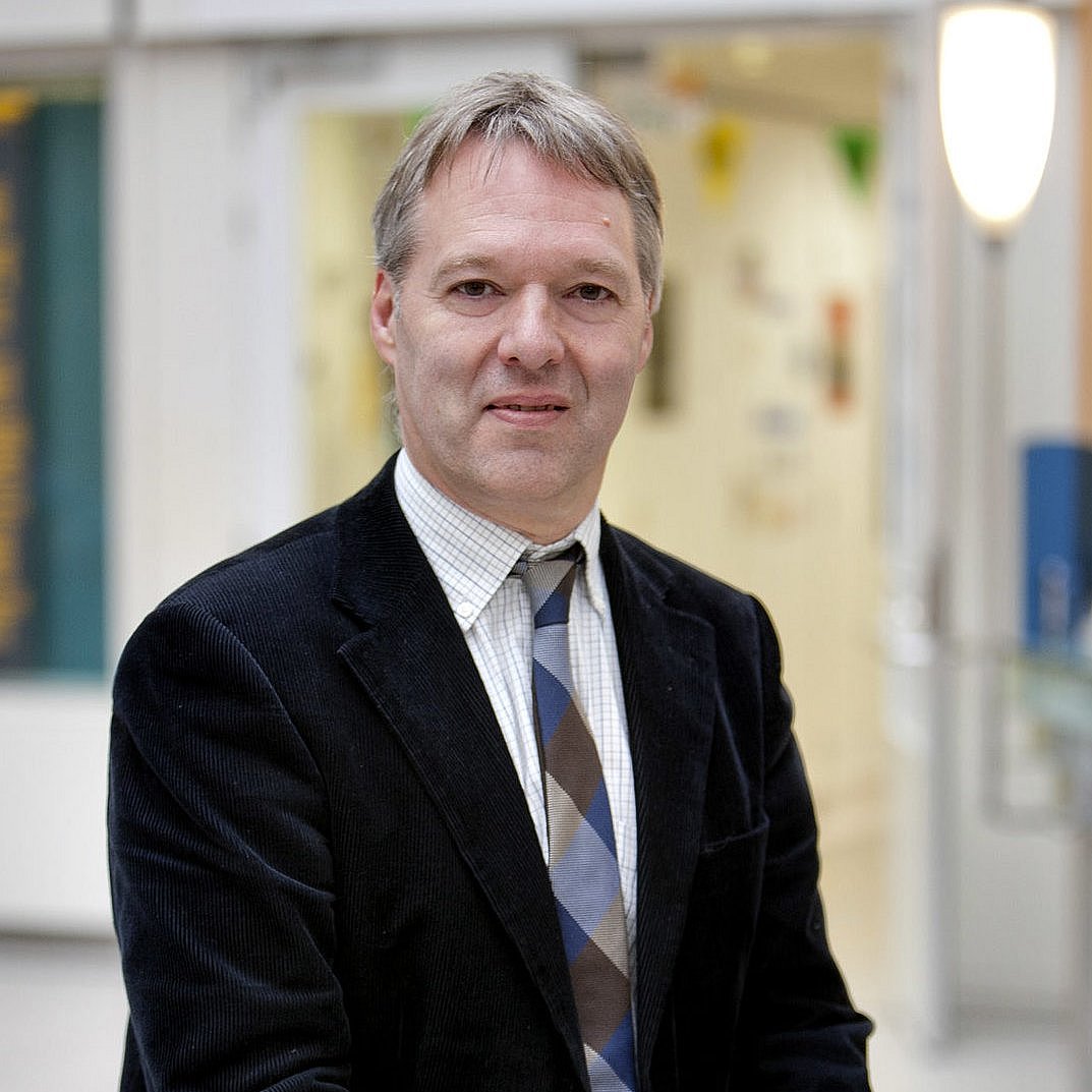 Portait of Prof. Luc Zimmermann in a suit and tie in a hallway