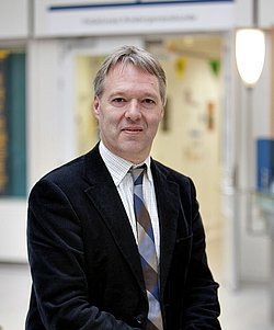 Portrait of Prof. Luc Zimmermann Portait of Prof. Luc Zimmermann in a suit and tie in a hallway