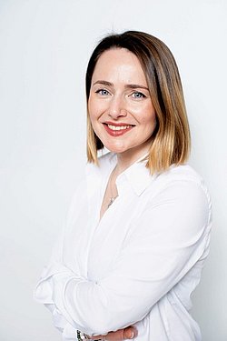 Oleksandra Balyasna Portrait Portrait of Oleksandra Balyasna smiling in a white blouse in front of a neutral background.
