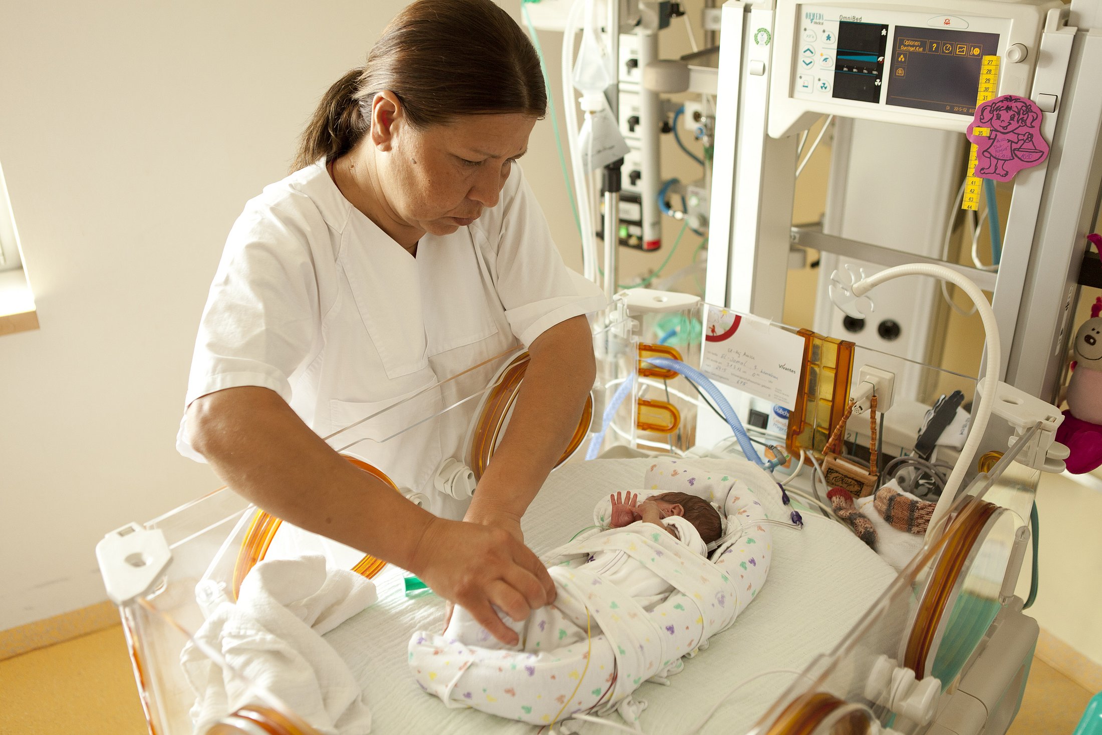 Nurse Providing Care in the Neonatal Unit Neonatal nurse gently cares for a preterm infant resting inside an incubator.