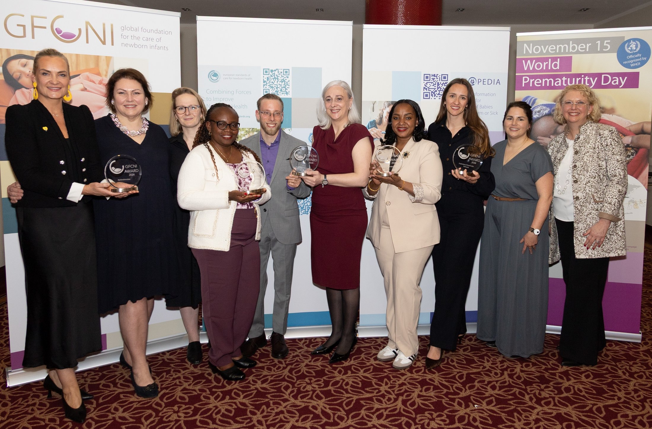 Award winners holding trophies at the GFCNI POS 2026 Awards Ceremony, standing together in front of event banners celebrating global advocacy in newborn health.