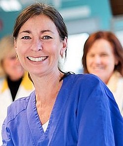 Portrait of Ann Hellström smiling in a clinical setting.