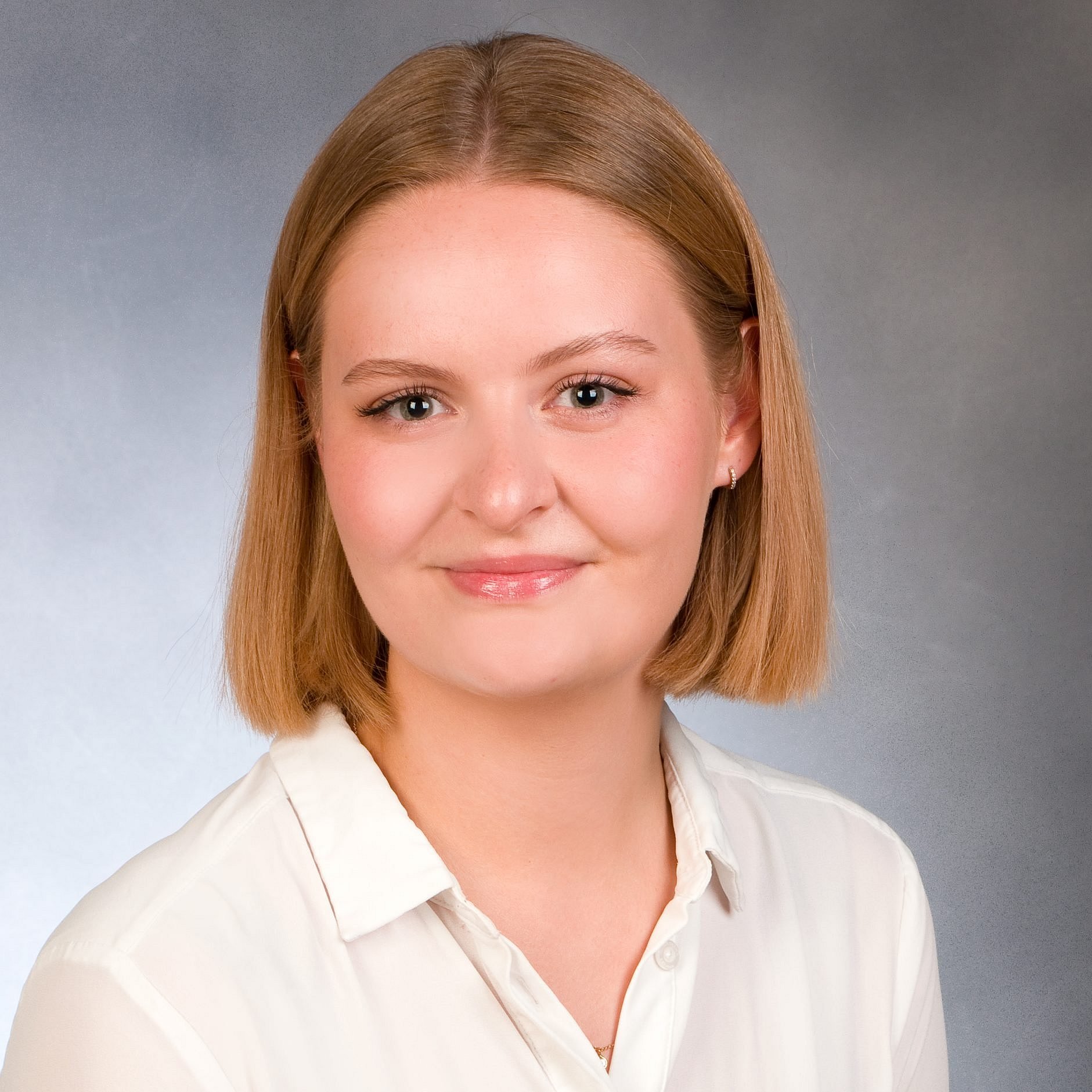 A professional headshot of Ruth Kemper, wearing a white blouse against a grey background.