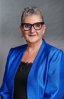 Professional portrait of Professor Linda Johnston wearing a blue blazer and black glasses. 