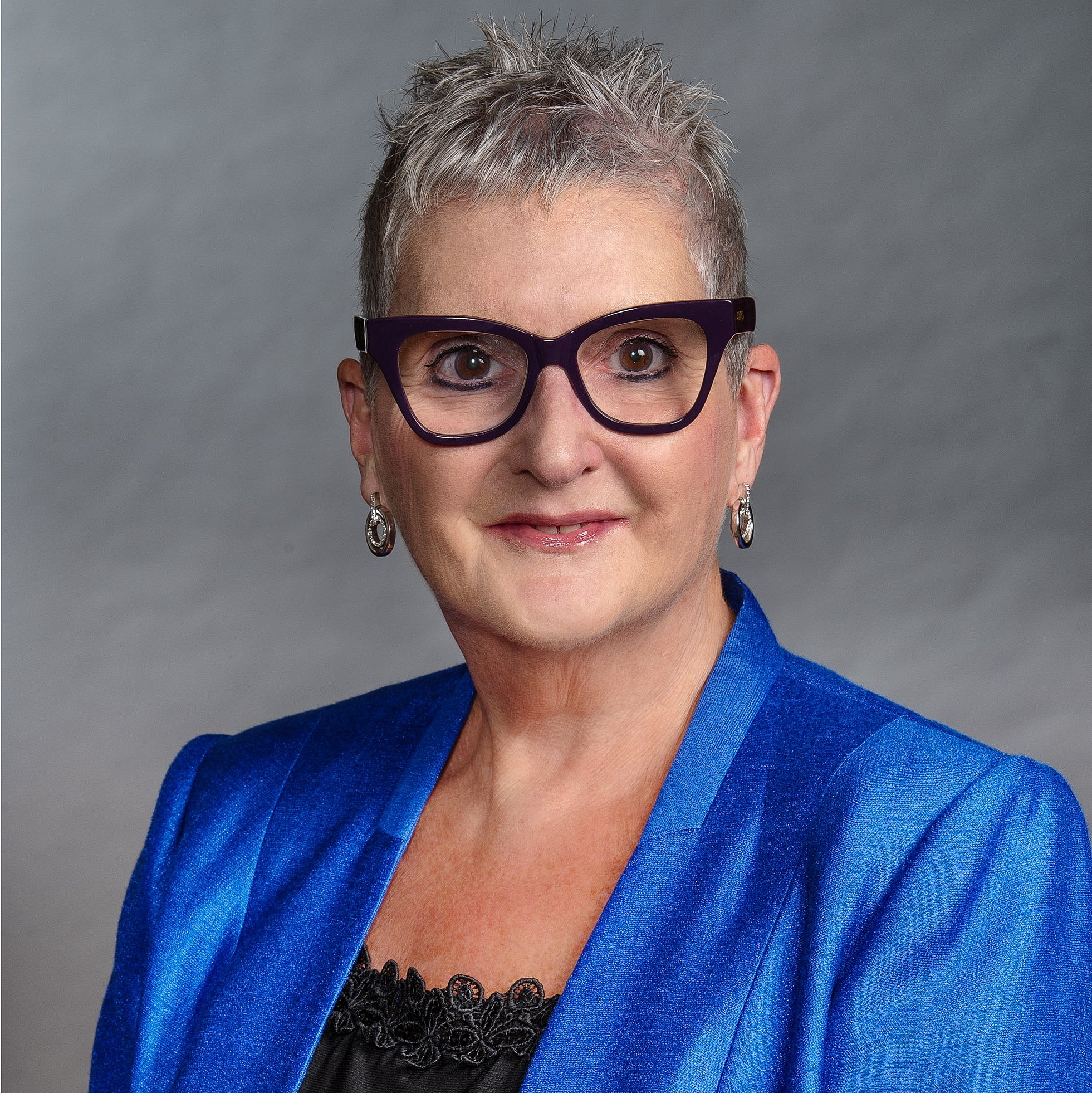 Professional portrait of Professor Linda Johnston wearing a blue blazer and black glasses. 