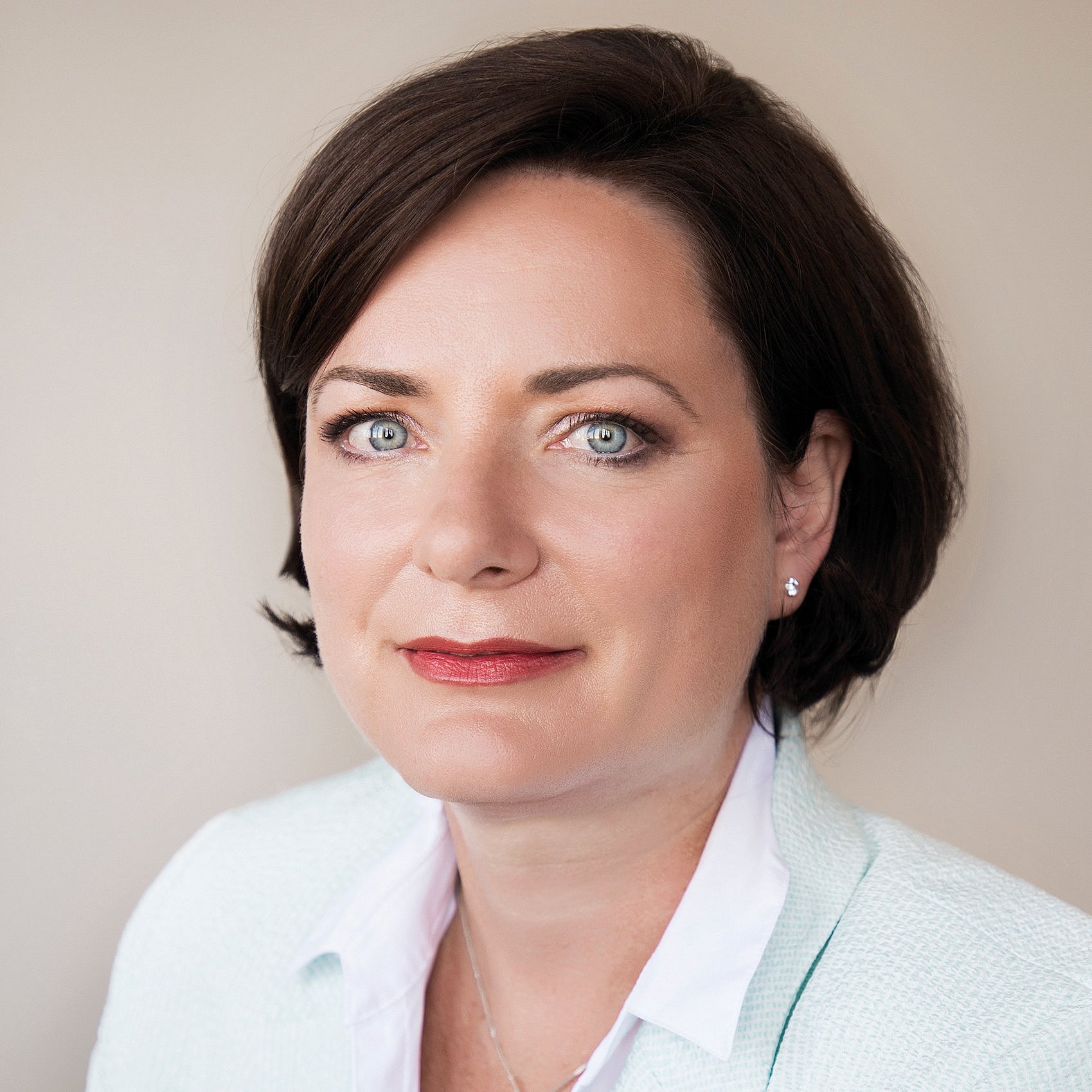 A professional headshot of Nicole Thiele, smiling in a soft green blazer and white blouse.