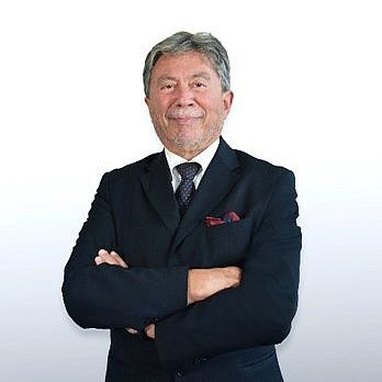 Portrait of Professor Moshe Hod wearing a black suit in front of a neutral background.