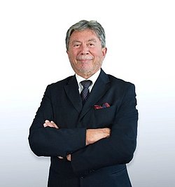 Portrait of Professor Moshe Hod wearing a black suit in front of a neutral background.
