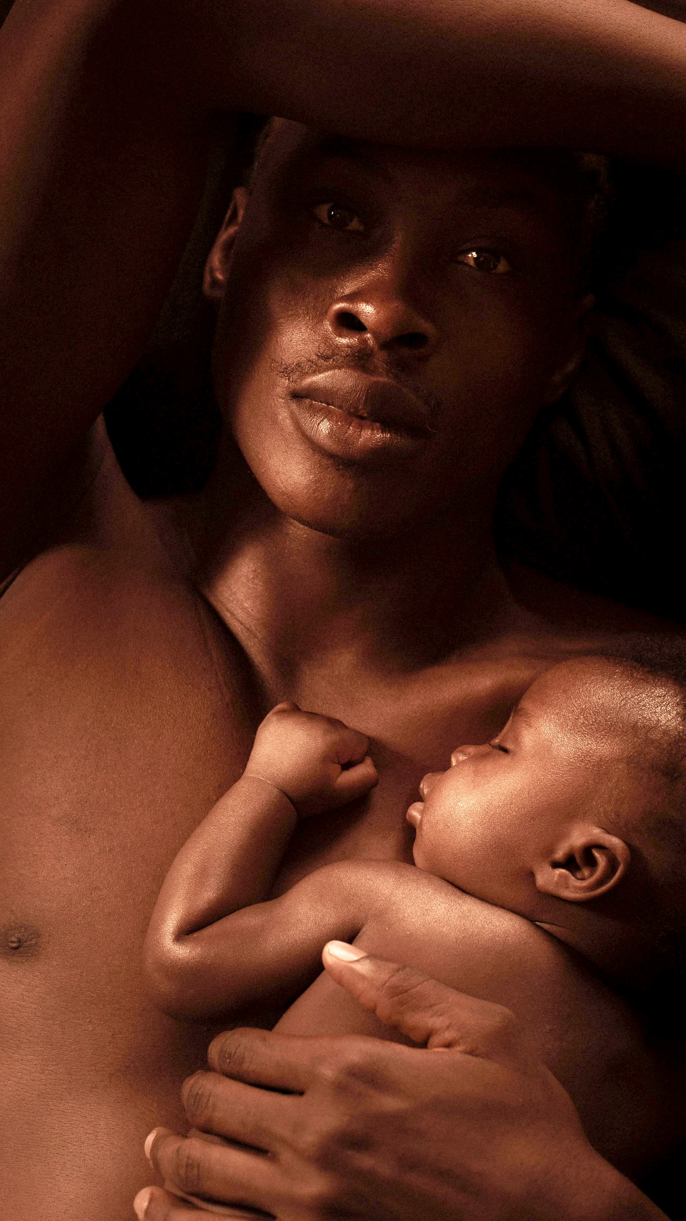 Newborn resting peacefully on father's bare chest during skin-to-skin contact, highlighting intimacy and early bonding. 
