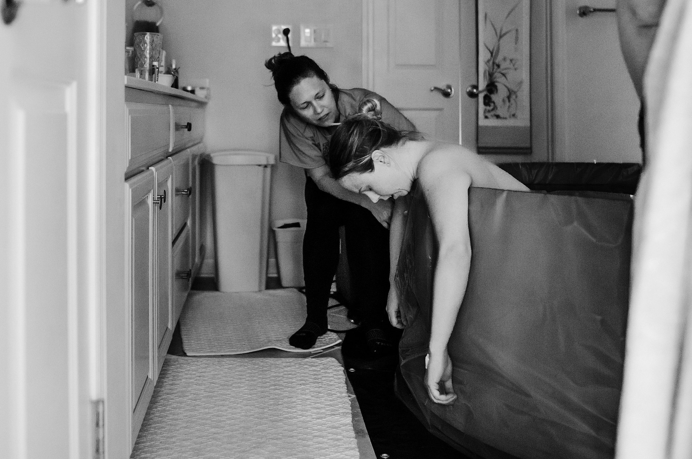 Woman receiving support during prolonged labor Woman leaning over a birthing pool while receiving support during labor.