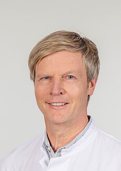 Portrait of Dr. Michael Poschmann Portrait of Dr. Michael Poschmann in a white coat smiling