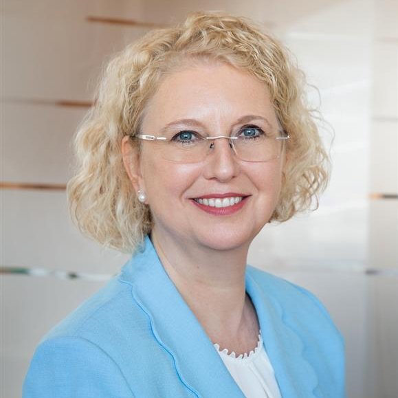 A professional headshot of Silke Mader, wearing glasses and a light pink blazer.
