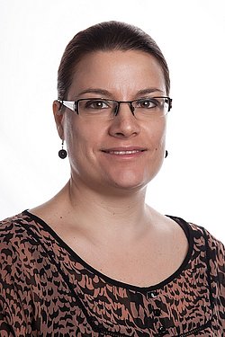 Nina Nikolova Professional Portrait of Nina Nikolova in a patterned blouse wearing glasses, looking confident.