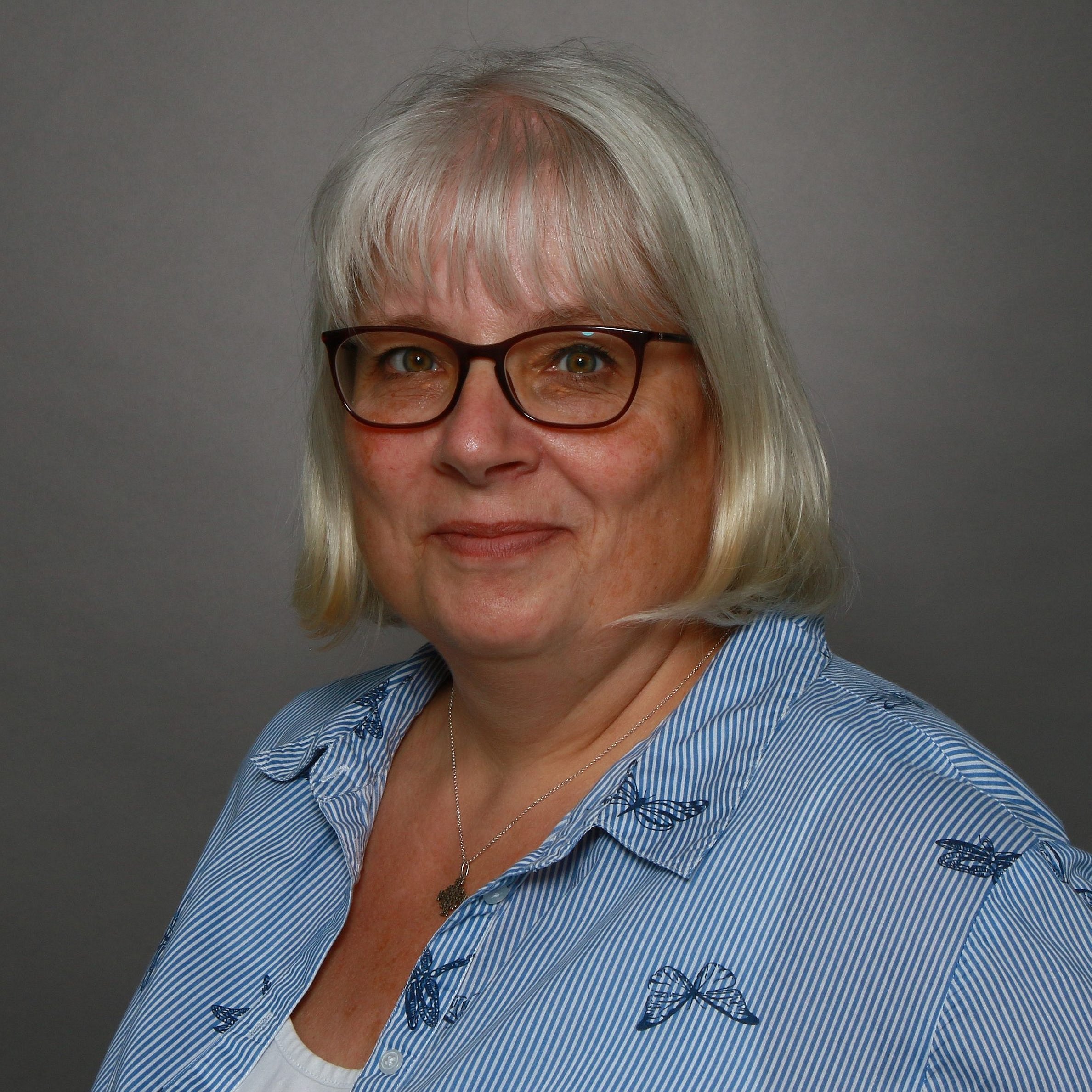 A professional headshot of Stefanie Gorbahn, wearing glasses and a striped shirt.