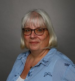 A professional headshot of Stefanie Gorbahn, wearing glasses and a striped shirt.