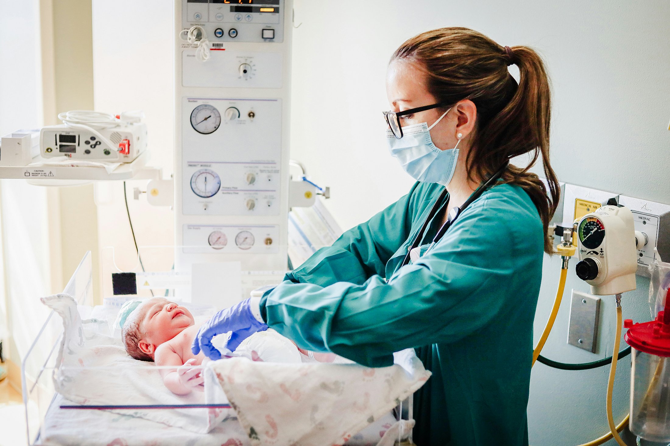 Neonatal Nursing Care in the NICU A neonatal nurse provides care to a newborn infant in a neonatal intensive care unit (NICU) surrounded by medical equipment. The image illustrates neonatal nursing care in a clinical setting and reflects the importance of managing nurse workload to support safe, reliable care.