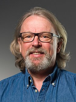 Portrait of Atle Moen wearing glasses and denim shirt.