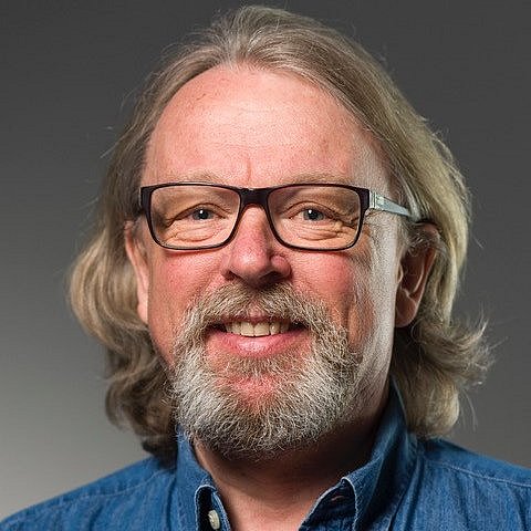 Portrait of Atle Moen wearing glasses and denim shirt.