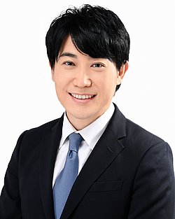 Portrait of Dr. Takeshi Arimitsu smiling and wearing a black suit and a blue tie.