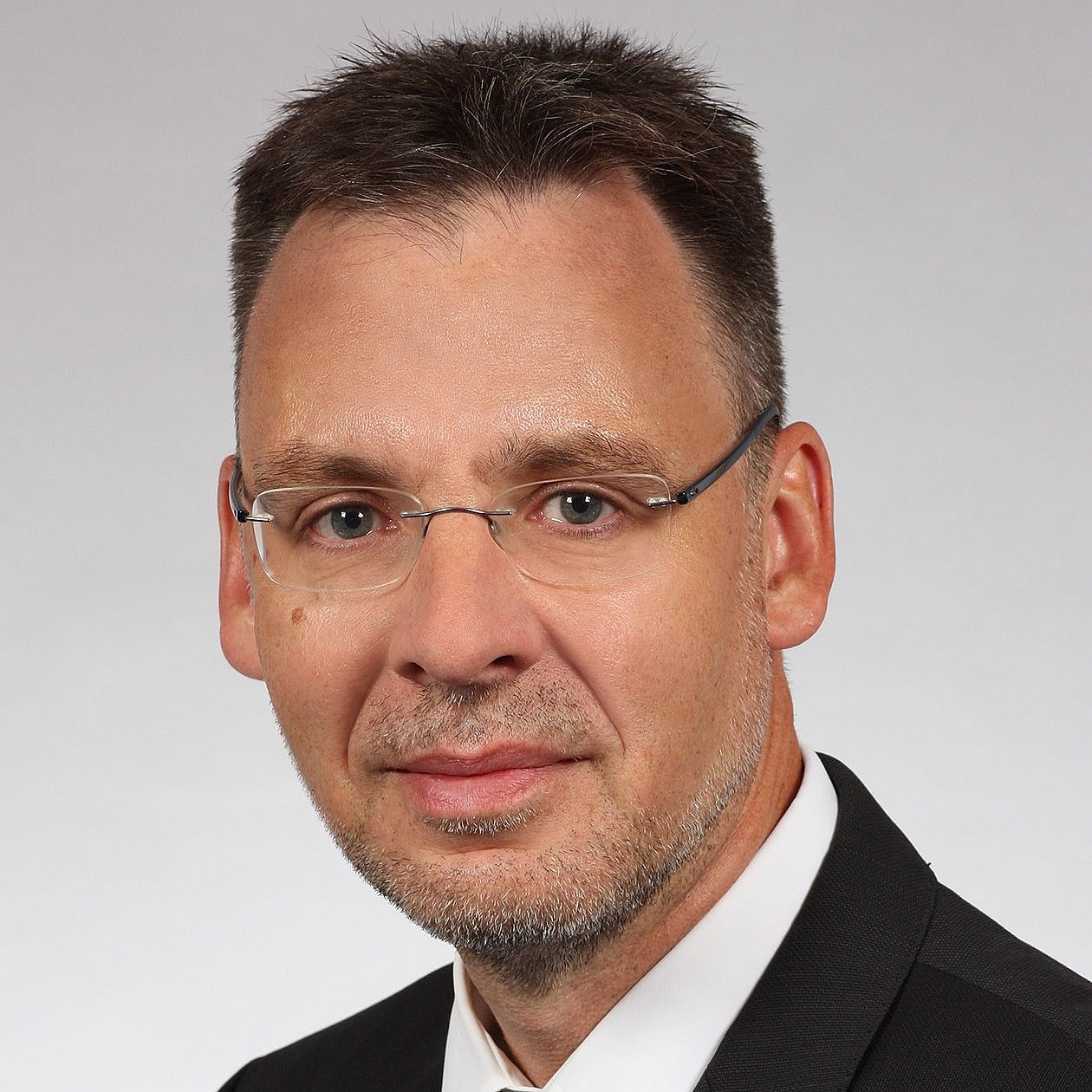 Portrait of Professor Mario Rüdiger wearing a black suit and a black tie.