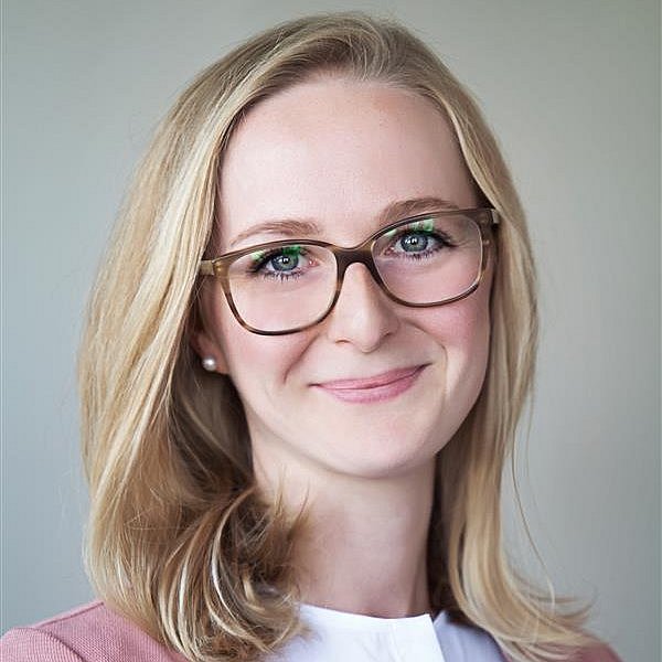 Portrait of Aurelia Abenstein with glasses and light background.