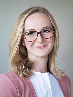 Portrait of Aurelia Abenstein with glasses and light background.