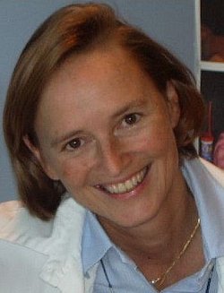 Portrait of Petra Hüppi smiling in a white coat.