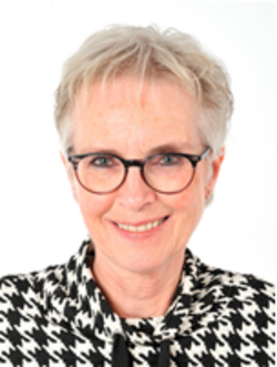 This is a portrait of Professor Agnes van den Hoogen, smiling and wearing glasses and a black-and-white patterned pullover.