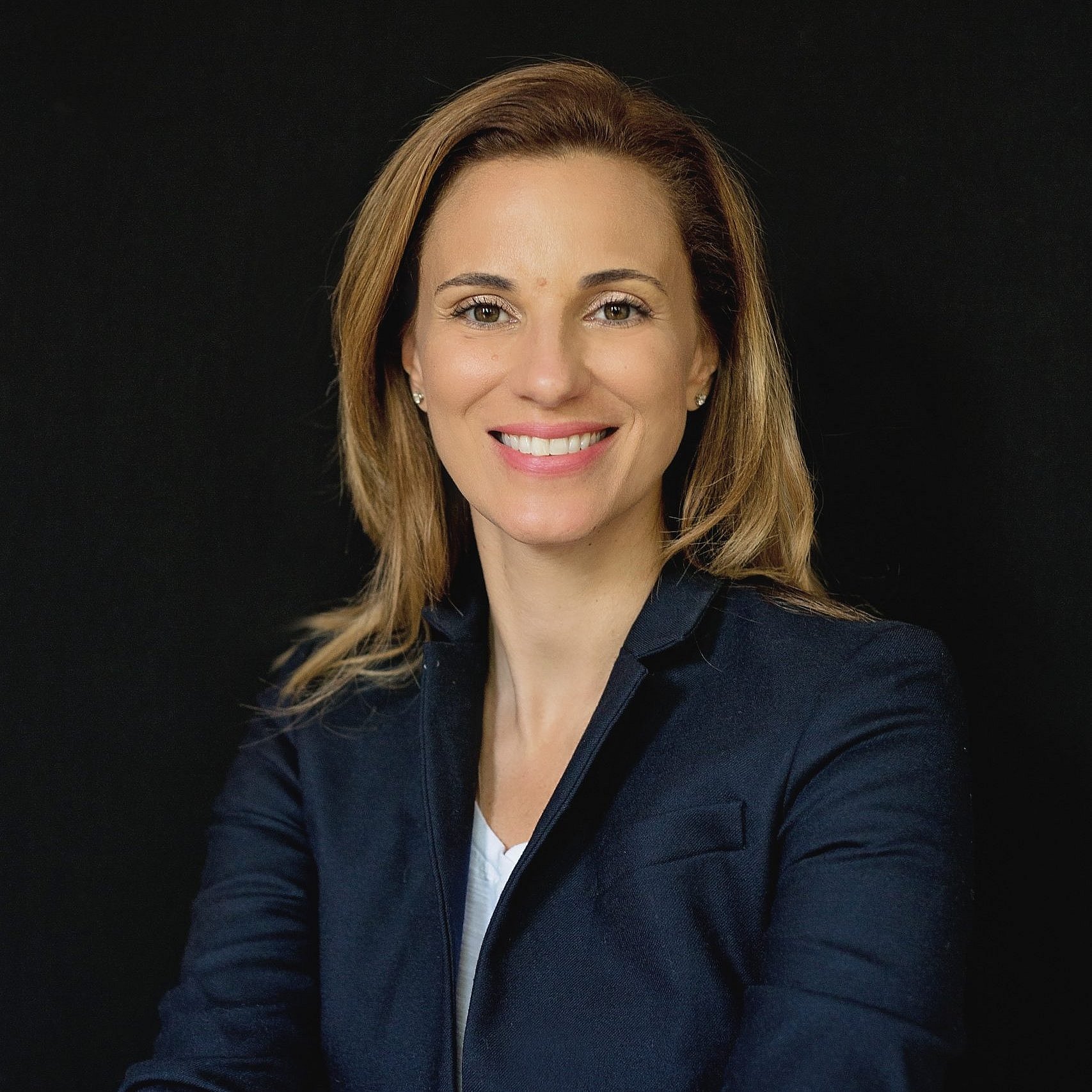 Fabiana Bacchini smiling in a black blazer with a dark background.