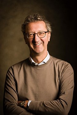 Professor Hans van Goudoever professional portrait with warm background.