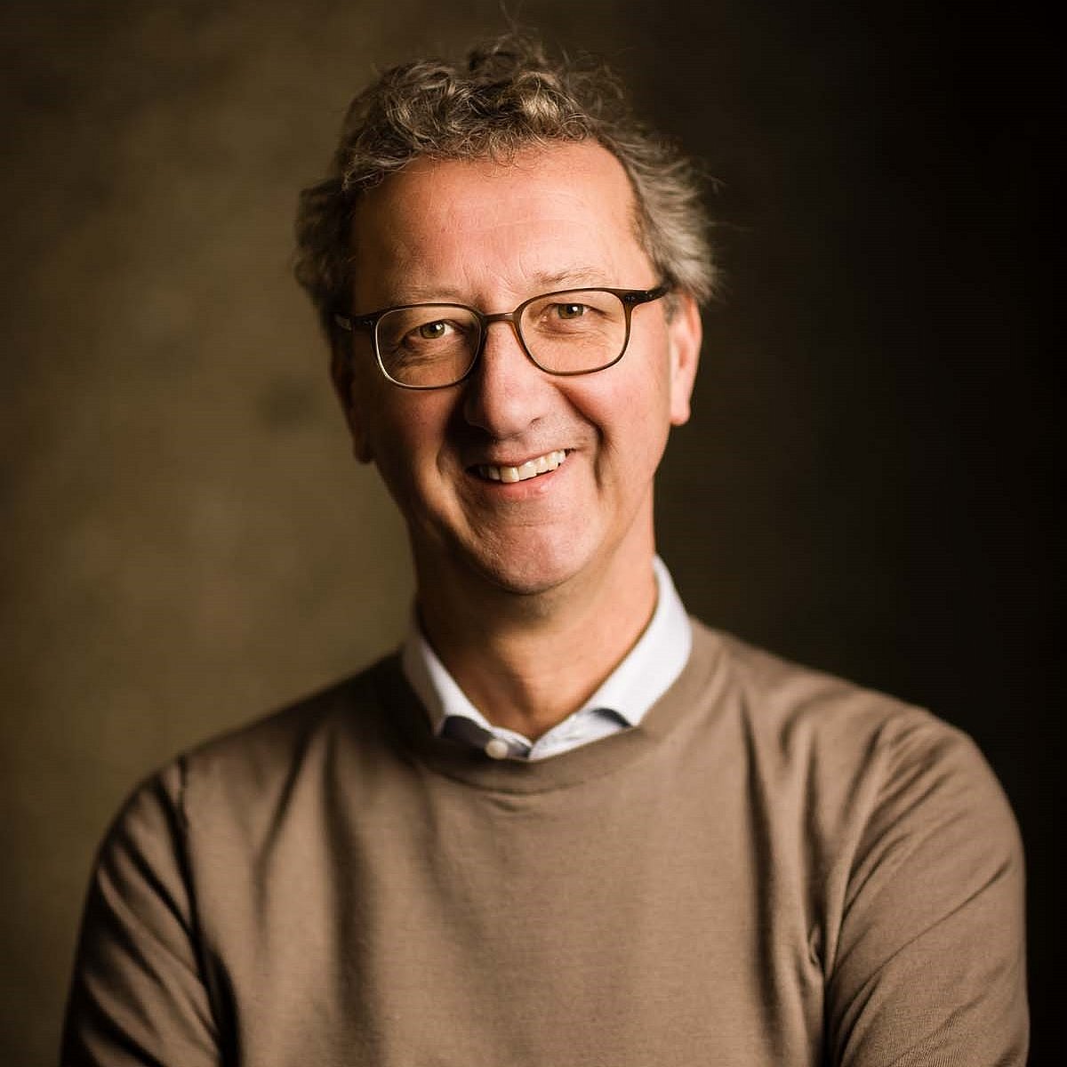 Professor Hans van Goudoever professional portrait with warm background.