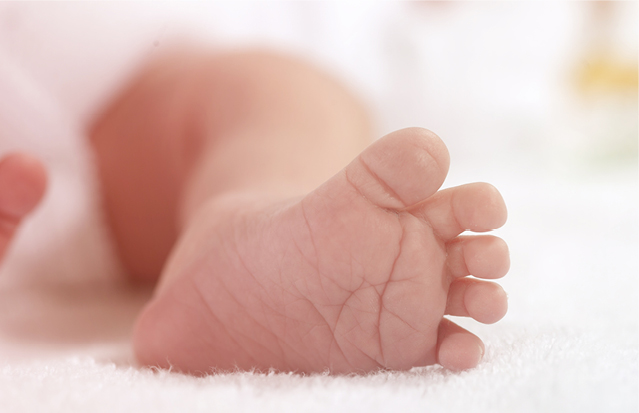 Close-up of a newborn’s tiny foot on a soft surface, highlighting the importance of neonatal care.