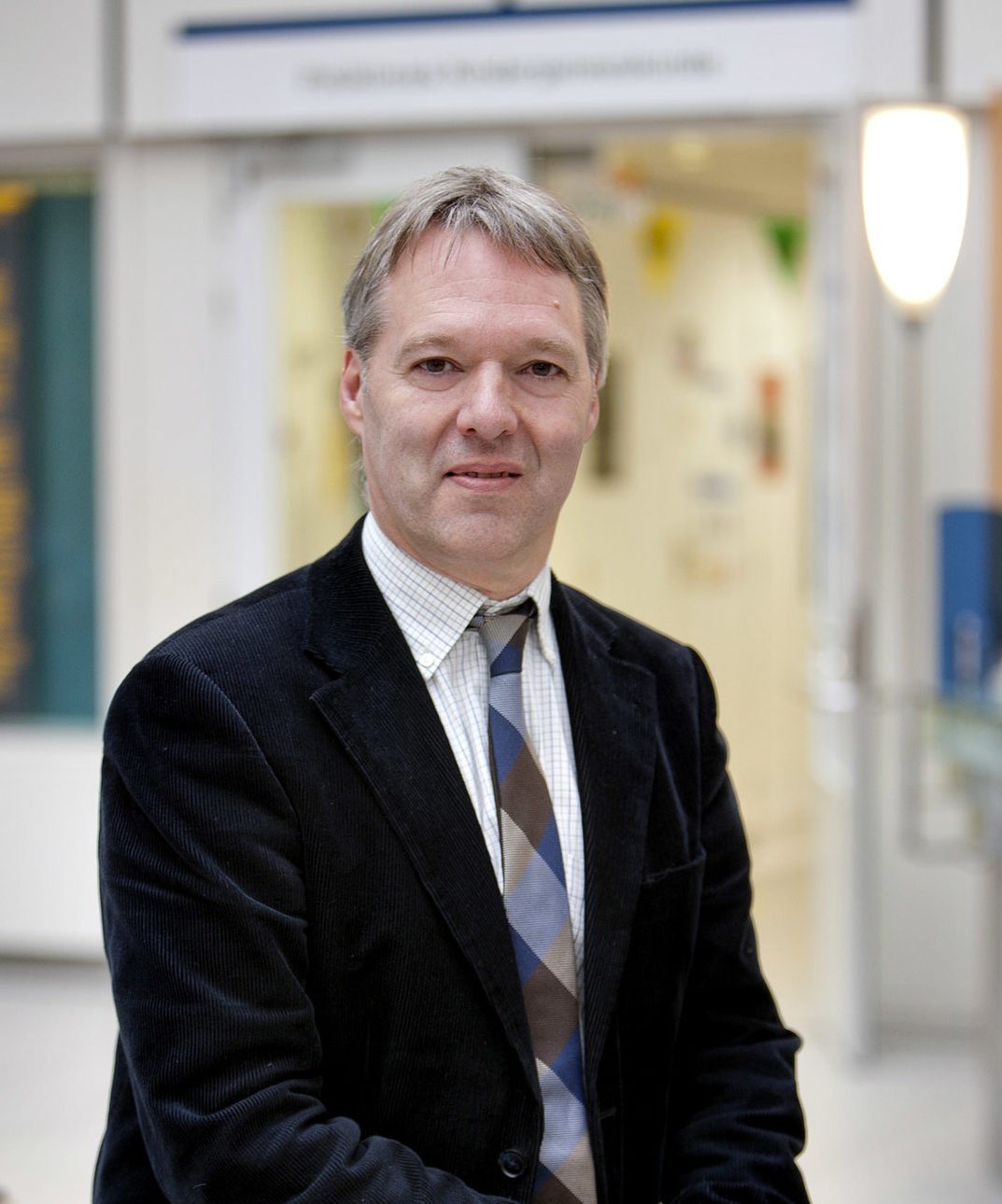 Portait of Prof. Luc Zimmermann in a suit and tie in a hallway