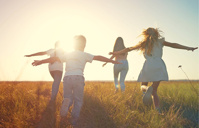 Children running through a sunlit field, representing a brighter future for newborns.