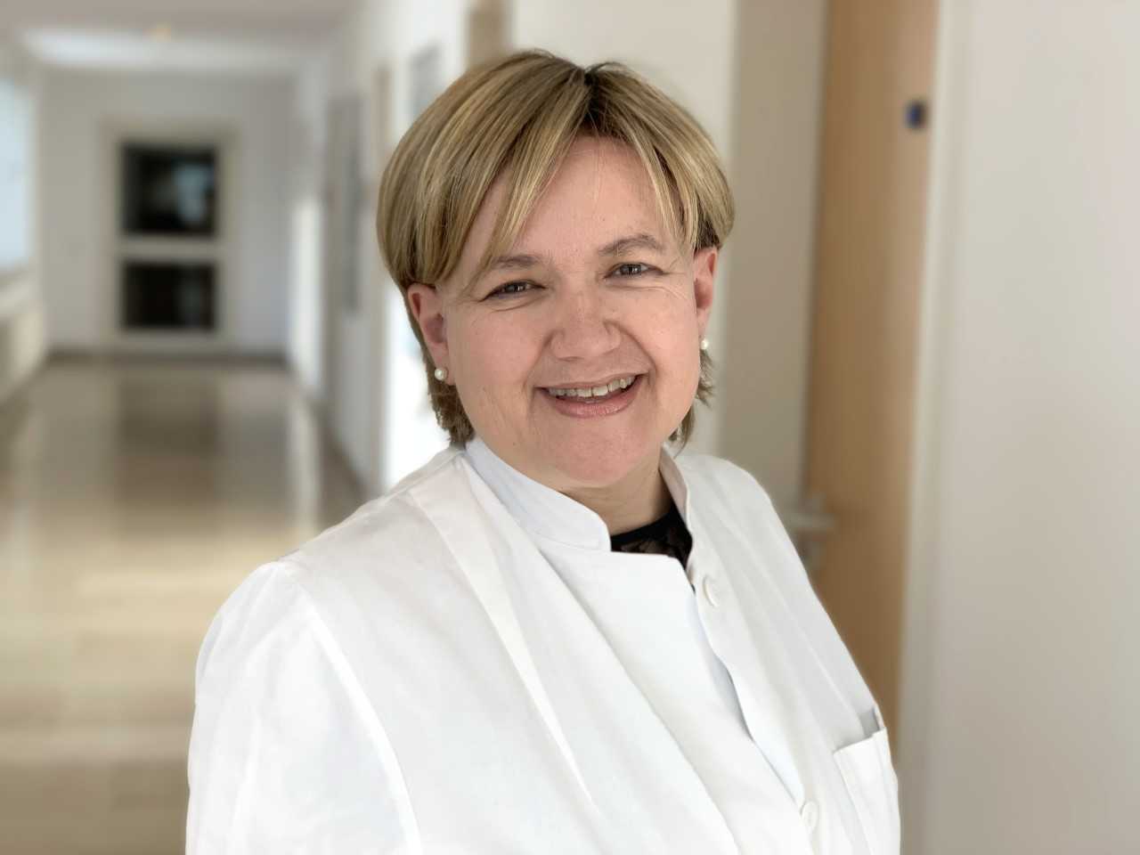 Portrait of Dr. Edith Reuschel in a white coat in a medical hallway.