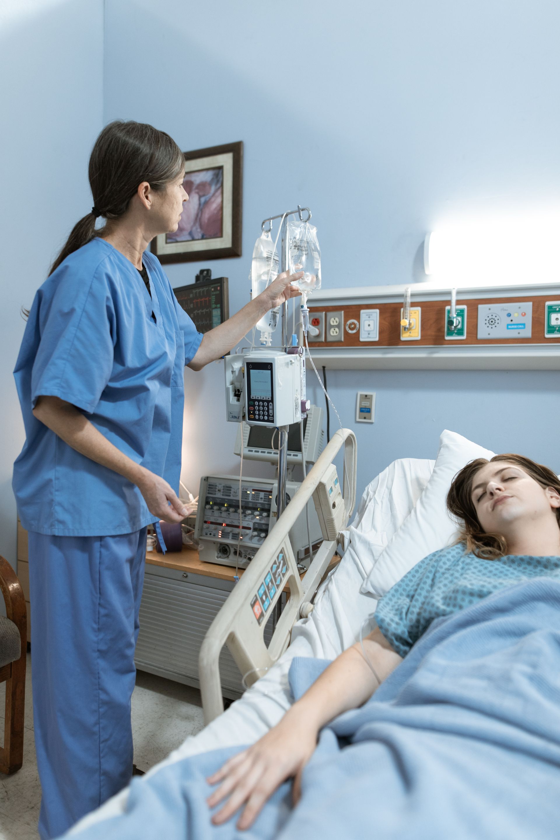 Hospital treatment for infection after childbirth Healthcare professional managing intravenous treatment for a patient resting in a hospital bed.