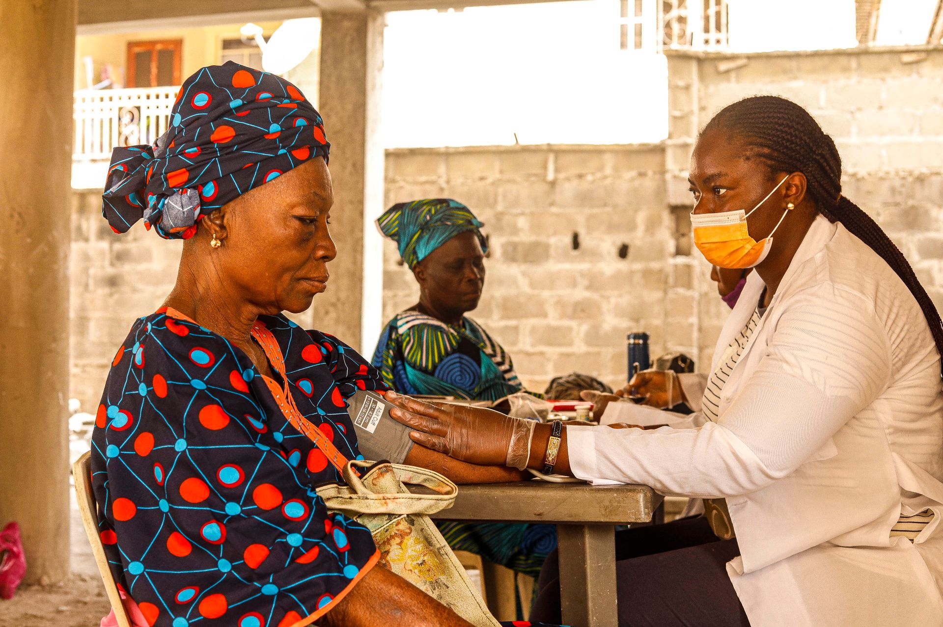 Maternal Health Screening in a Community Clinic Healthcare professional measuring a woman’s blood pressure during a community health screening.