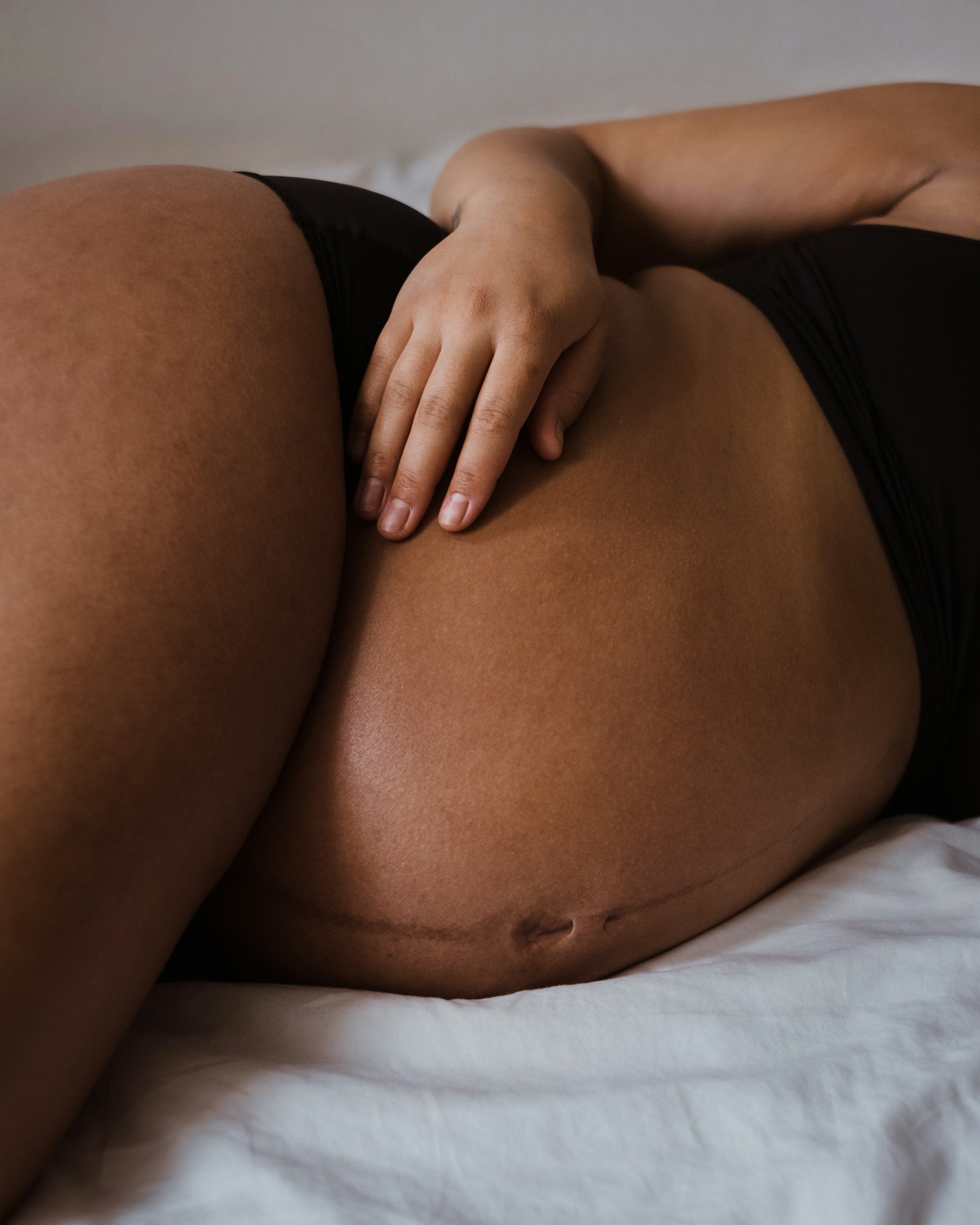 Close-up of a pregnant woman resting with one hand gently placed on her belly.