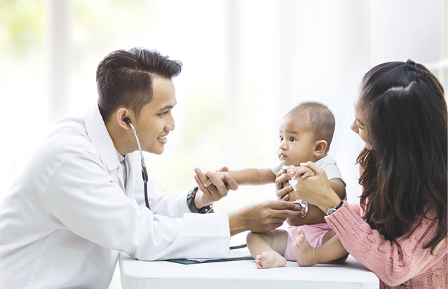 Doctor examining a baby during a healthcare visit with the mother present.