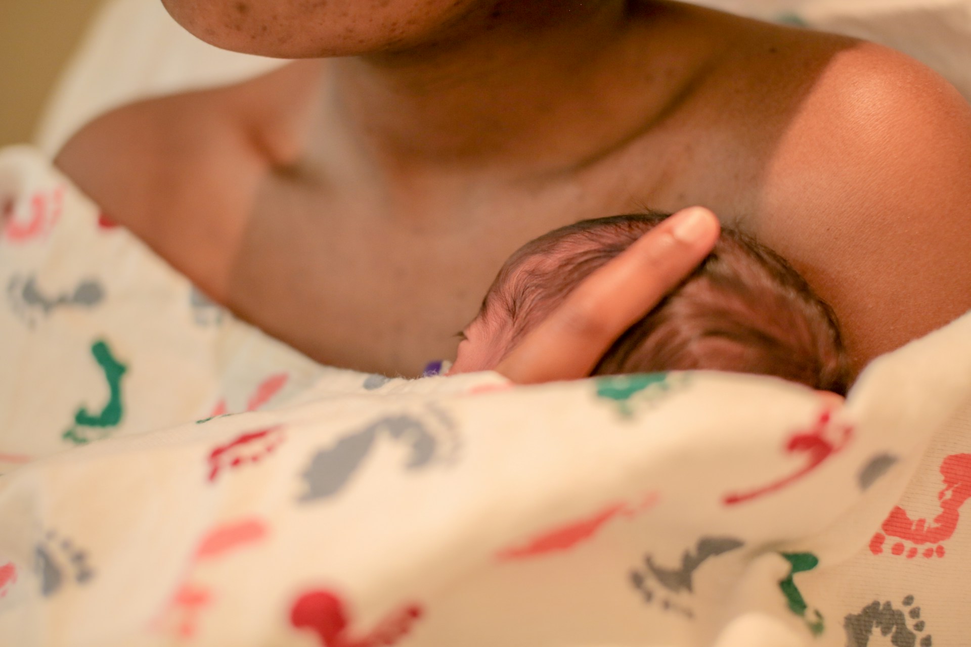 Newborn Breastfeeding During Early Postpartum Care Close-up of a newborn breastfeeding while supported by the mother’s hand.