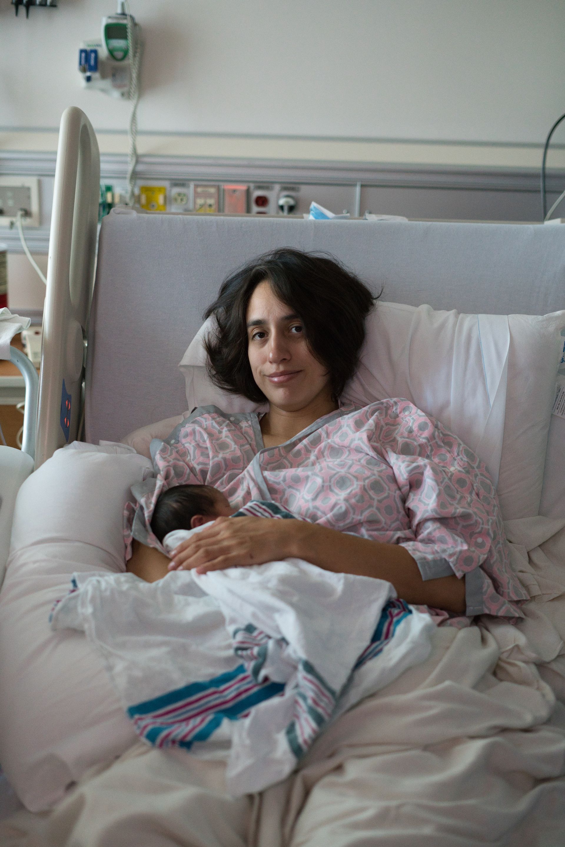 Mother Breastfeeding Her Newborn After Birth Mother breastfeeding her newborn while resting in a hospital bed after childbirth.
