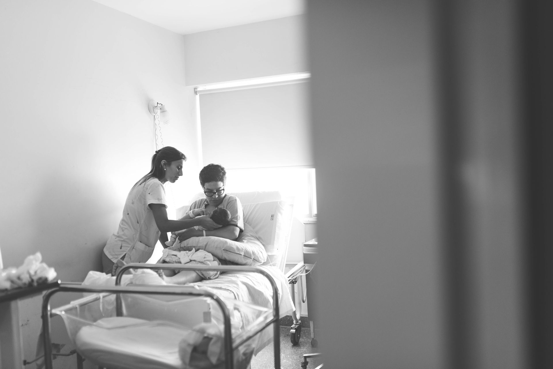 Healthcare Professional Supporting Breastfeeding After Birth Healthcare professional helping a mother breastfeed her newborn in a hospital room.