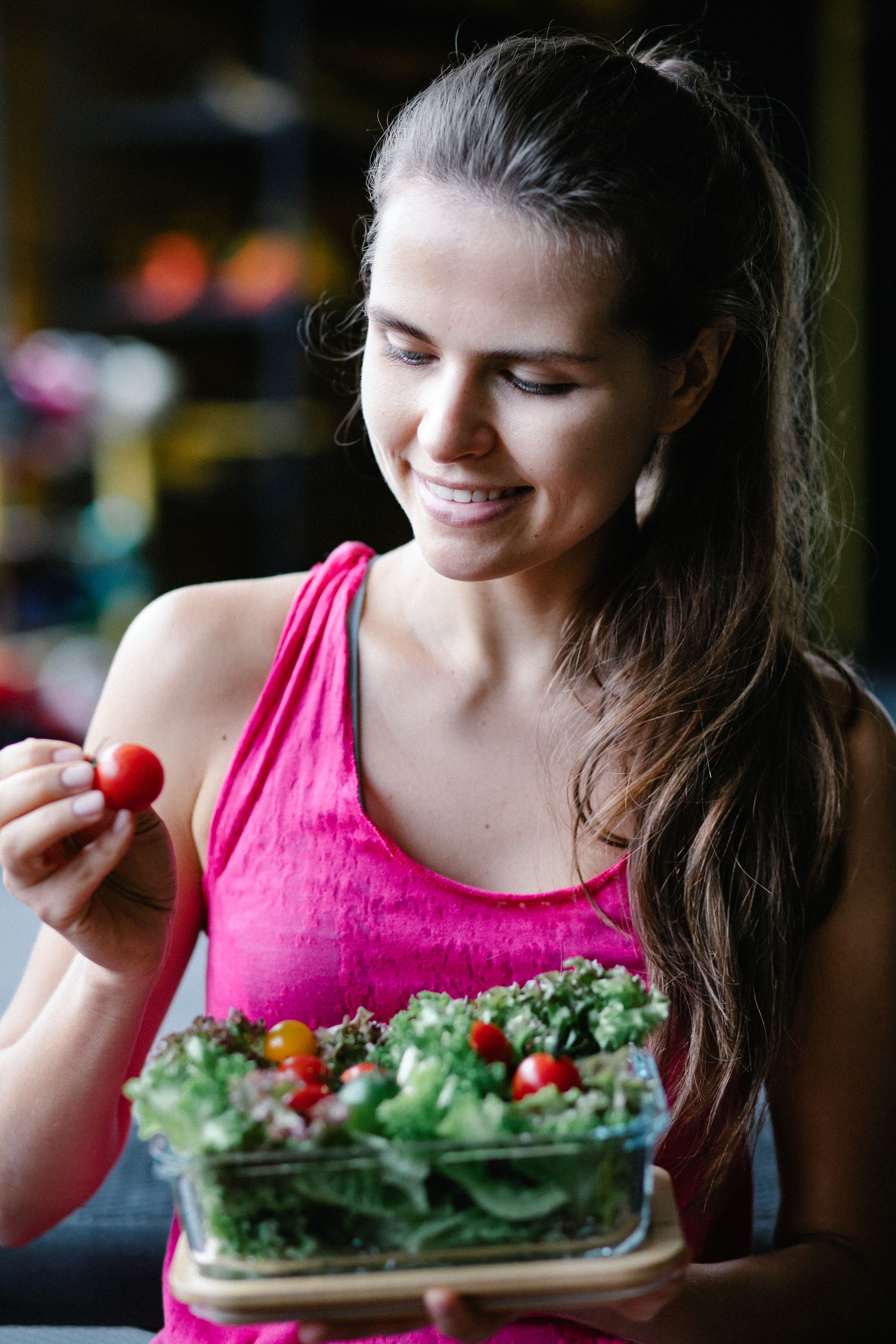Healthy nutrition and lifestyle before pregnancy Woman holding a fresh salad and choosing a tomato as part of a healthy diet.