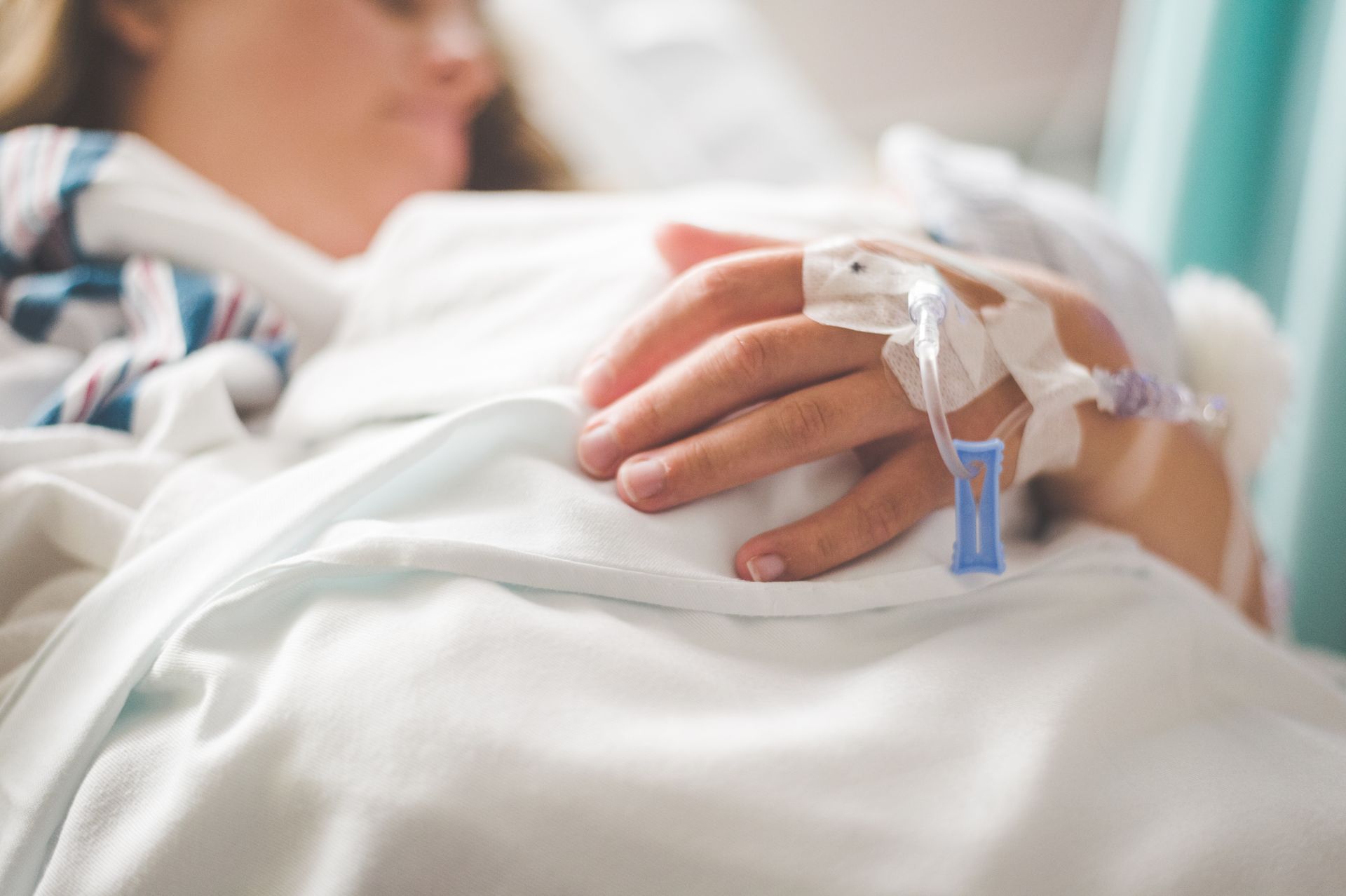 Pregnant patient receiving hospital treatment Patient resting in a hospital bed with an intravenous line attached to the hand.