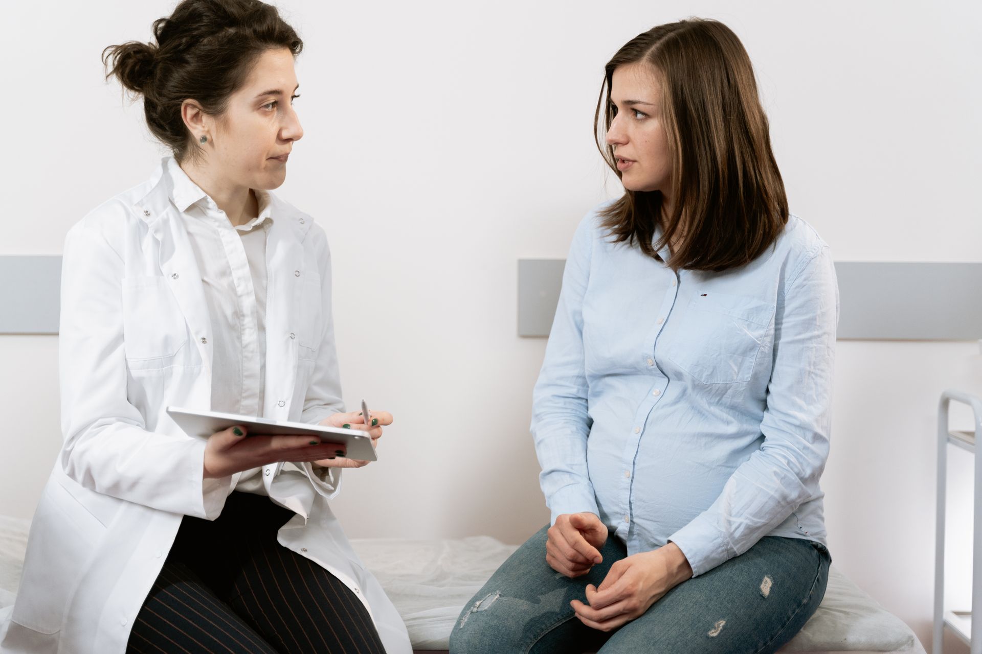 Prenatal consultation between a pregnant woman and healthcare professional Expectant parent holding two printed ultrasound images of a developing baby.