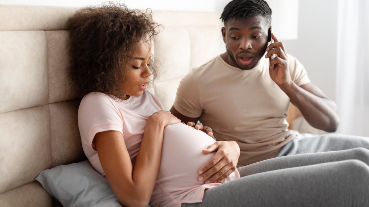 Recognizing possible signs of preterm labor Pregnant woman experiencing discomfort while her partner calls for medical assistance.