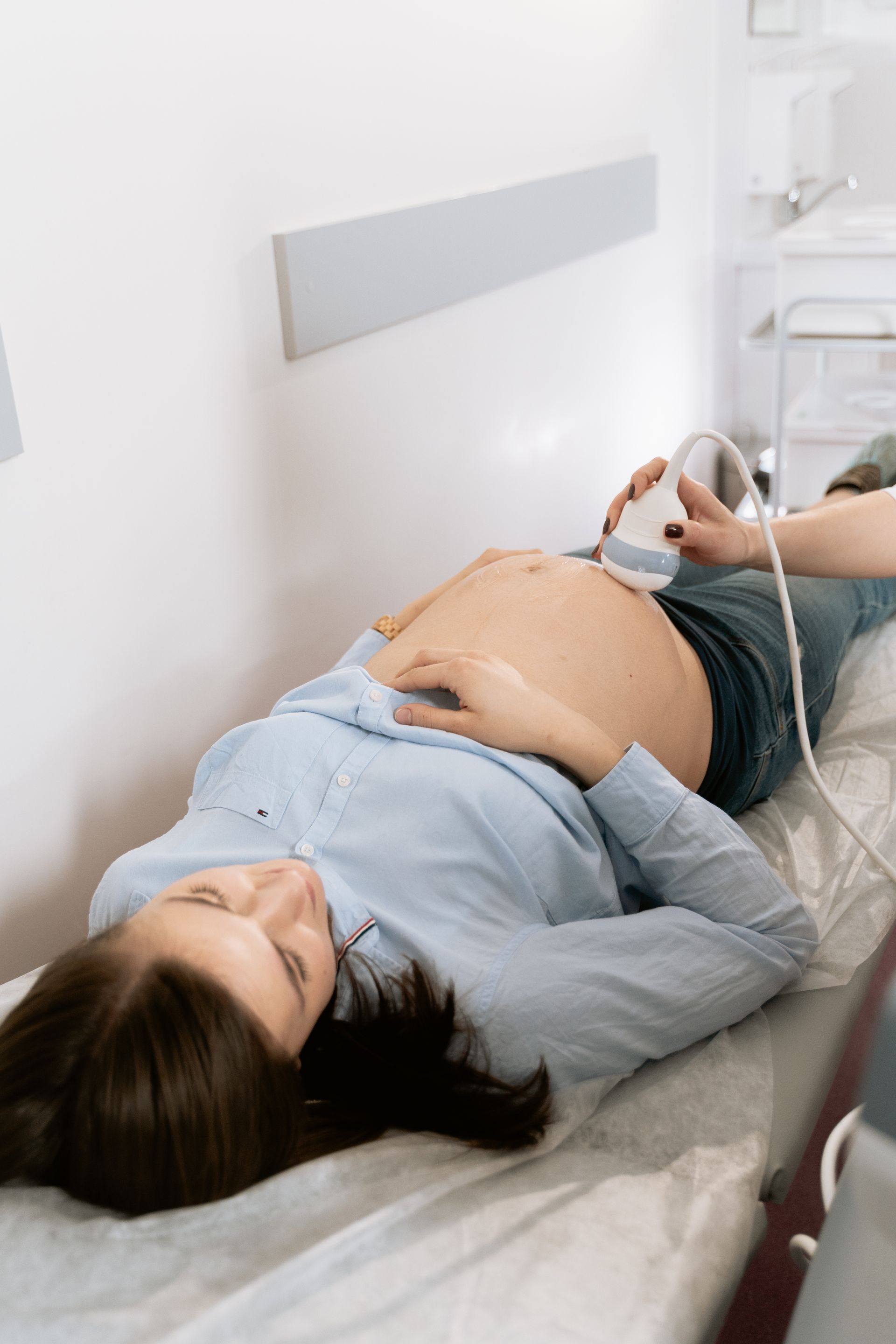 Prenatal Ultrasound Examination Pregnant patient lies on an examination table while a clinician performs an abdominal ultrasound.